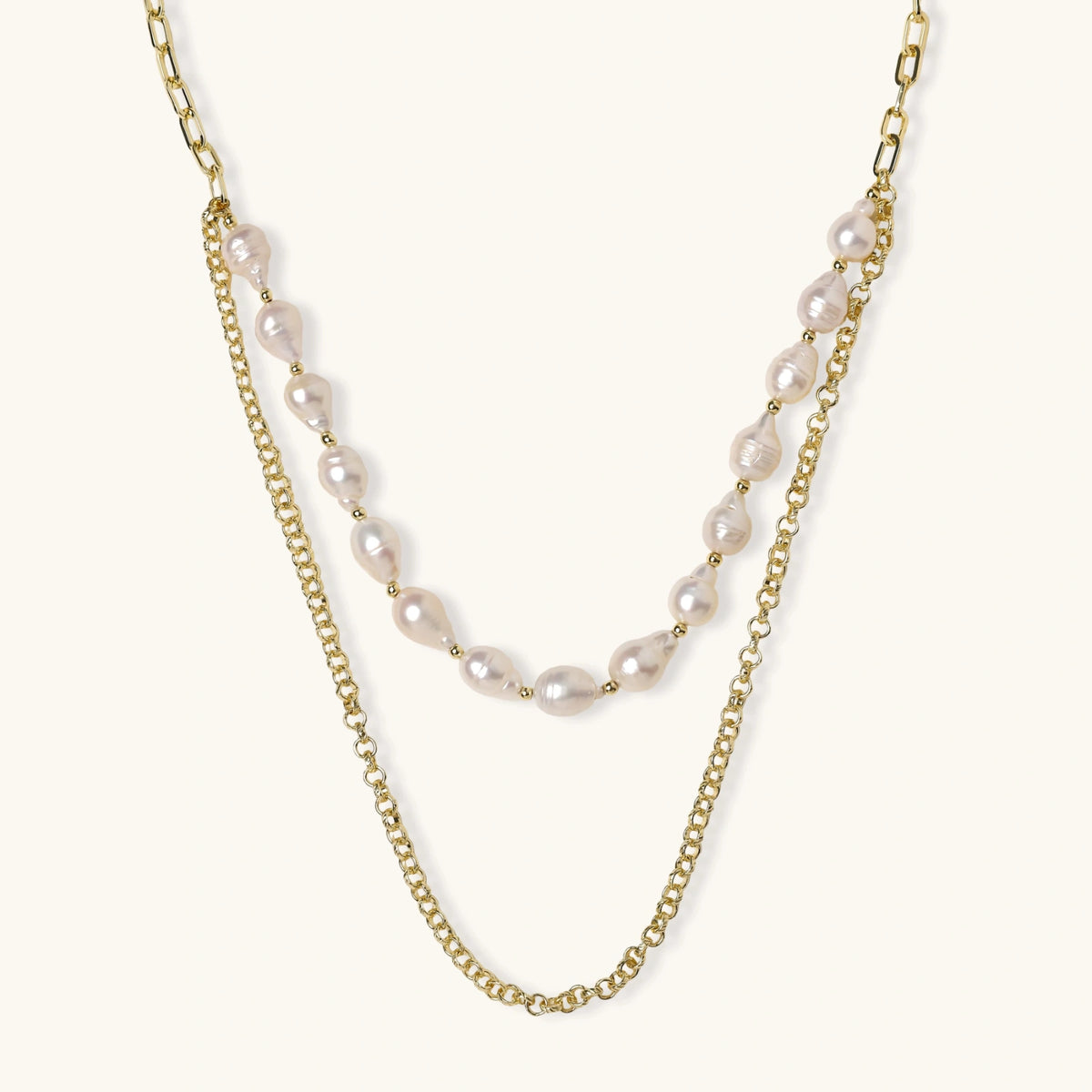 Layered gold chain necklace with organic baroque freshwater pearls and adjustable length on cream background