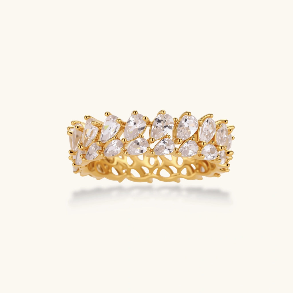 Adjustable gold-plated ring with double-row pear-shaped cubic zirconia stones in geometric pattern on cream background.